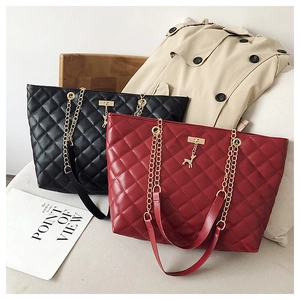 Detail of diamond quilted tote bags in black and red with gold chain and deer pendant