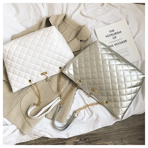 Detail of white and silver quilted chain tote bags with gold hardware and lock