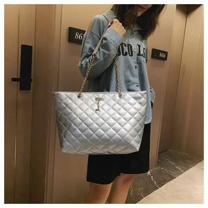 Silver quilted tote bag detail with gold deer pendant and metallic chain shoulder strap