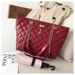 Detail of red quilted tote bag with golden deer pendant and metal chain strap