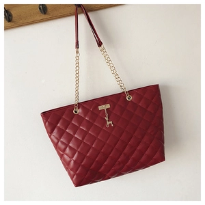Detail of burgundy quilted tote bag with gold chain strap and deer charm ornament
