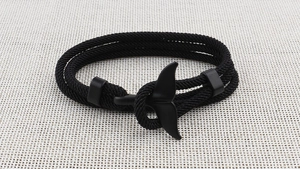 Close-up of black braided rope bracelet featuring a sleek whale tail metal clasp