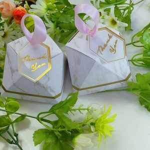 Close-up of marble pattern diamond wedding favor box with pink ribbon and gold trim