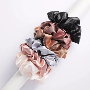 Detailed view of six premium silk-like satin scrunchies displayed on a white stand