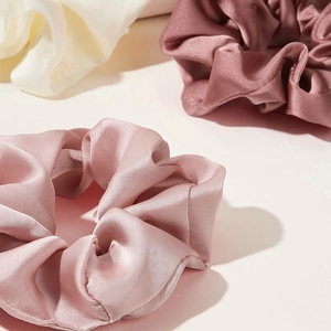 Detailed view of glossy satin scrunchies in soft pink and morandi dusty rose hues
