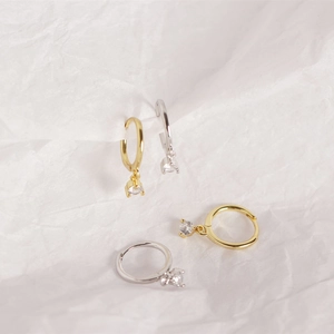 Detailed view of silver and gold huggie hoop earrings with sparkling round cubic zirconia