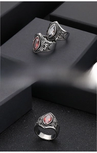Close-up of vintage stainless steel rings with marquise-cut red ruby and engraved patterns