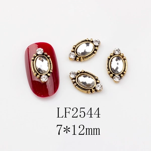 Macro shot of 7x12mm vintage gold oval nail charm with crystal inlay and small rhinestones