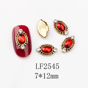 Detail of oval red gemstone nail art charms with vintage gold setting and rhinestones