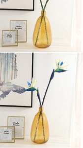 Detail of bird of paradise faux flowers in a textured brown bubble glass vase decor