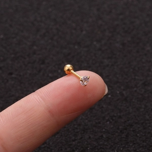Dettaglio ravvicinato di un orecchino a perno geco dorato con zircone sulla punta del dito