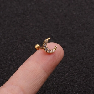 Macro primo piano di un orecchino a bottone a luna dorata con zirconi cubici incastonati