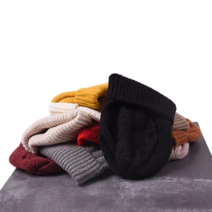 Detailed view of various color cable knit beanies stacked on stone surface