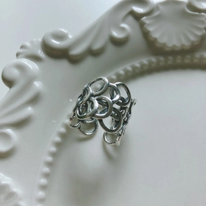 Minimalist 925 sterling silver interlaced ring set on vintage embossed ceramic plate