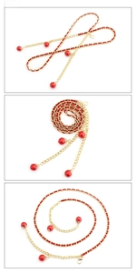 Detail of red ribbon woven with golden metal chain belt and large pearl pendants