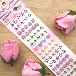 Close-up of pink dimensional stickers with purple flowers and stars on wood background