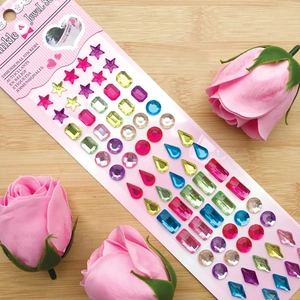 Detail of colorful acrylic jewel stickers in various shapes on a wooden surface