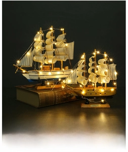 Détail de modèles de voiliers en bois avec lumières LED sur fond de livres anciens