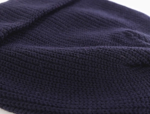Close-up of navy blue knit beanie showing fine vertical texture and premium stitching