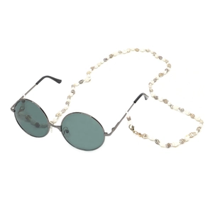 Detail of round sunglasses with a delicate white seashell eyewear chain and metal frame