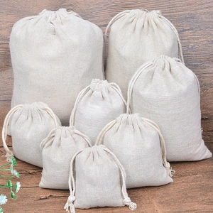 Natural cotton linen drawstring pouches in various sizes displayed on wood background