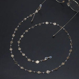 Gold glasses chain with hollow roses and clear beads on a black background