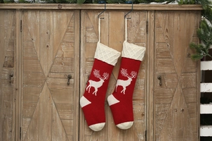 Detail of red knit Christmas stockings with white reindeer patterns on wooden background