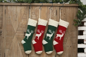 Detail of four knitted Christmas stockings with reindeer patterns on a wooden cabinet