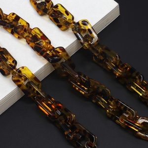 Polished tortoiseshell acrylic glasses chain with rectangular links on a minimal background