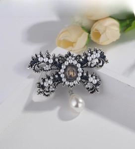 Detailed macro of vintage baroque bow brooch with blue rhinestones and pearl drop