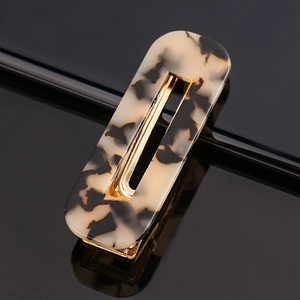 Detail of a rectangular acetate hair clip with leopard print and golden metal clip