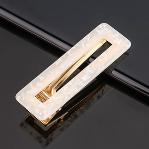 Macro detail of rectangle acetate hair clip with white stone texture and gold metal spring