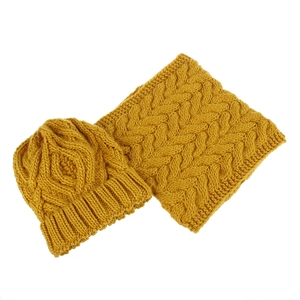 Close-up of mustard yellow chunky knit beanie and matching loop scarf with cable patterns