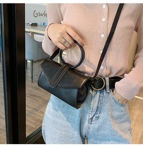 Dettaglio di una mini borsa strutturata in pelle nera con manico tondo e tracolla