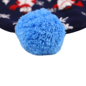 Macro shot of a fluffy blue pom-pom on top of a Christmas knit hat with festive patterns