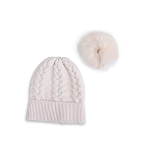 Berretto in maglia a trecce color crema con soffice pompon su sfondo bianco