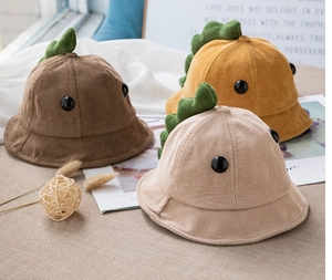 Nahaufnahme der Kinder-Fischerhüte aus Cord mit Dinosaurier-Motiv in Braun, Beige und Gelb