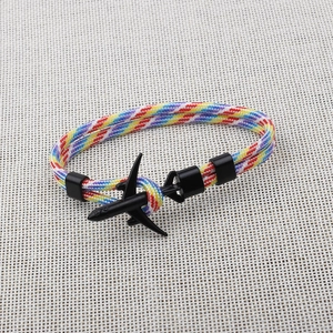 Close-up of rainbow braided paracord bracelet featuring a matte black airplane metal charm