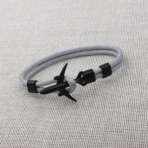 Detail showing grey parachute cord weave and black metal airplane charm on bracelet