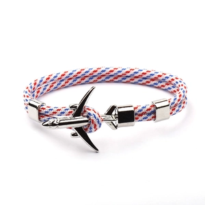 Detail of red white and blue braided cord bracelet with silver airplane and anchor clasp