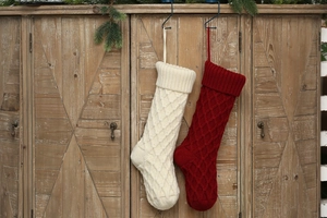 Nahaufnahme von rot-weißen Strick-Weihnachtssocken mit Rautenmuster an einem Holzschrank