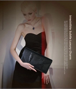 Detail of black faux crocodile leather clutch featuring a 3D crocodile head emblem