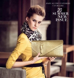 Detail of gold faux crocodile skin clutch with decorative golden crocodile metal clasp