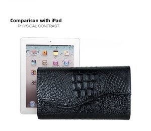 Size comparison showing black crocodile texture clutch bag next to a standard tablet