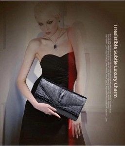 Detail of luxury black crocodile embossed clutch featuring 3D metal crocodile emblem