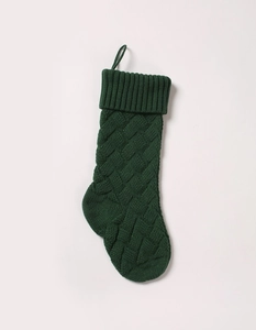 Macro detail of a green cable knit Christmas stocking with textured weave and hanging loop