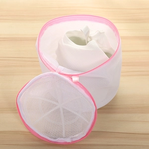 Detailed view of white mesh laundry bag with pink trim and zipper on wood background