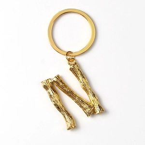 Detailed close-up of golden metal letter N keychain featuring a textured branch design