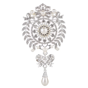 Elegant silver brooch with pearls, crystals, bow knots and teardrop pendant on white background