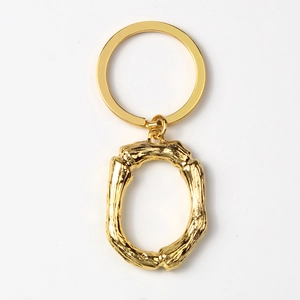 Detailed view of gold alloy letter O keychain with unique branch texture on white background